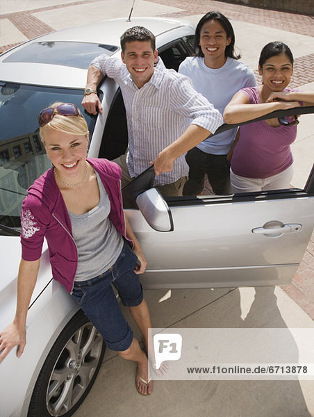 Multi-ethnic friends leaning on car