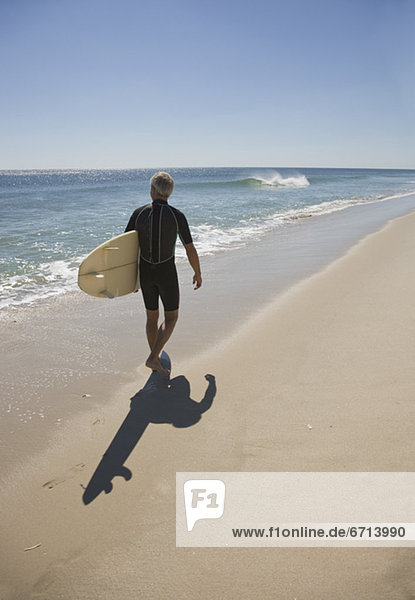 Man carrying surfboard at beach