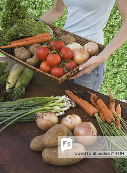 Woman holding basket of fresh vegetables