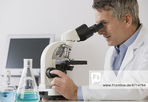Male scientist looking in microscope