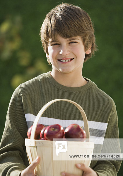 Junge hält Korb von Äpfeln