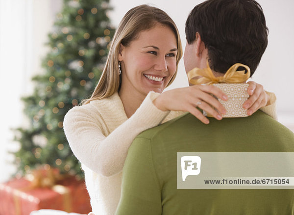 Woman holding gift and hugging husband