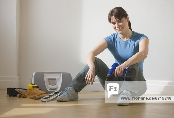 sitzend  Frau  Boden  Fußboden  Fußböden  halten  Bohrmaschine  Bohrer  schnurloses Telefon