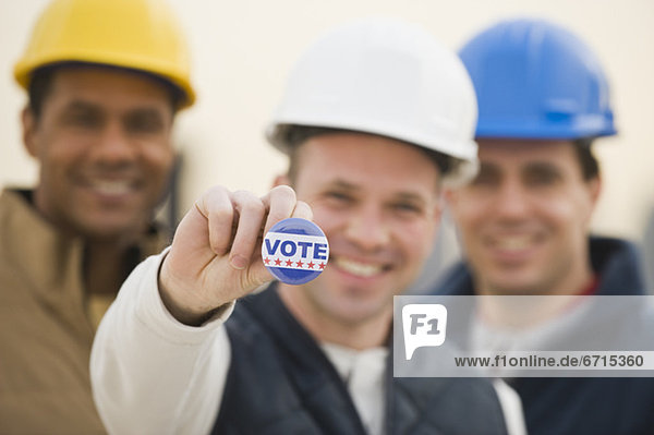 Multi-ethnic construction workers with Vote button