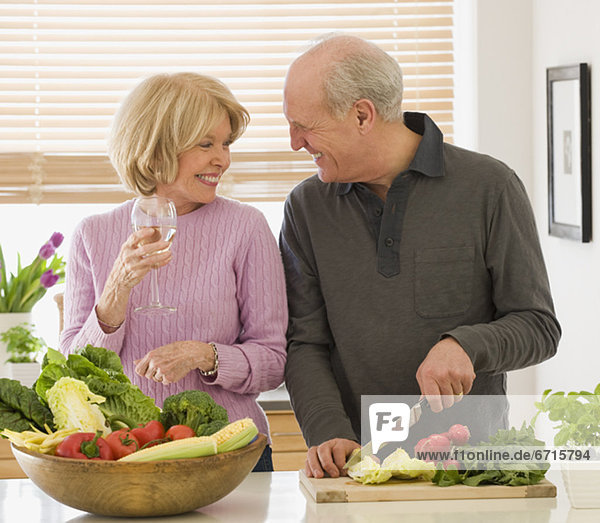 Senior couple chopping vegetables and drinking wine
