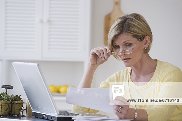 Woman reading mail next to laptop