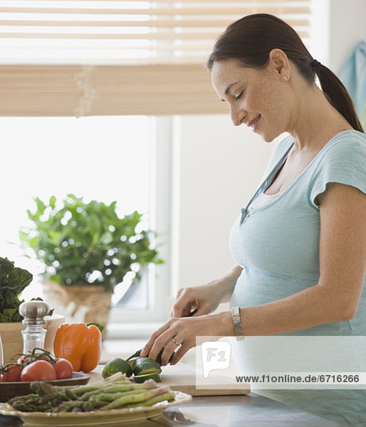 Pregnant Hispanic woman chopping vegetables