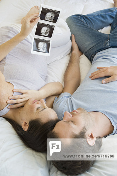 Pregnant Hispanic couple looking at ultrasound printout
