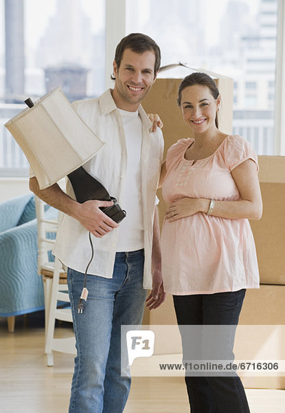 Pregnant Hispanic couple in new house