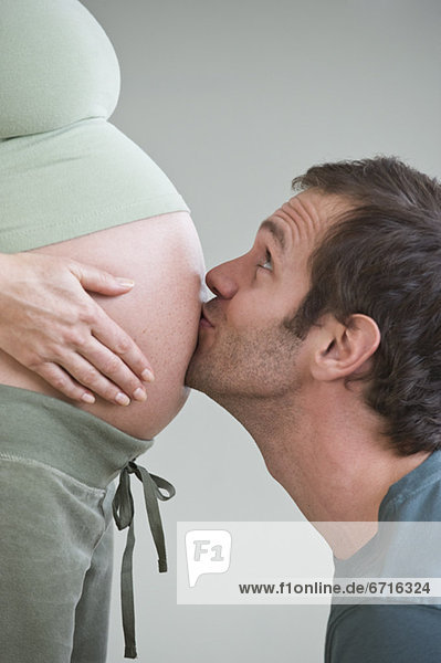 Hispanic man kissing pregnant wifeÕs belly