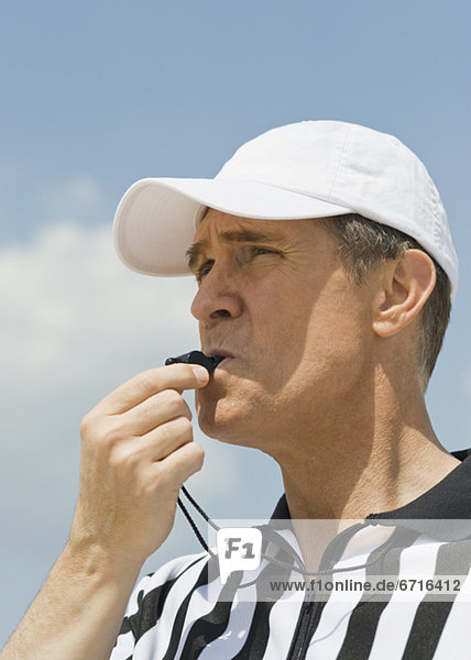 Male referee blowing whistle