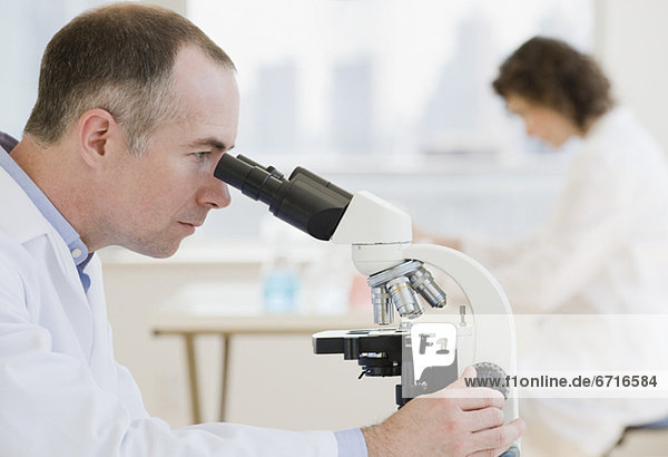 Male scientist looking into microscope