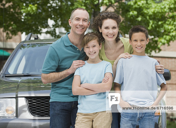 Family with two children in front of car