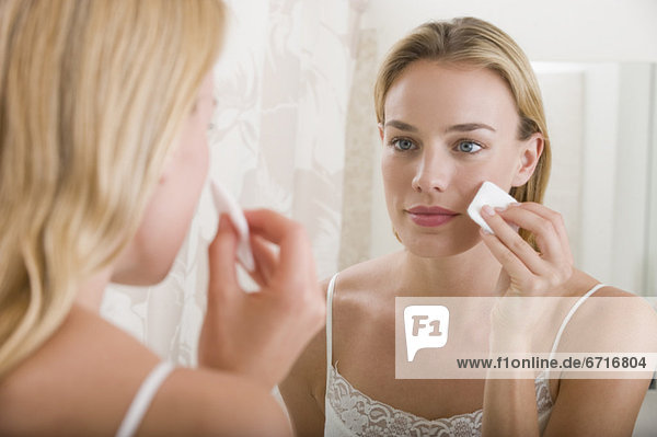 Woman applying makeup in bathroom