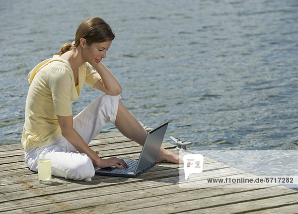 Woman using laptop on dock