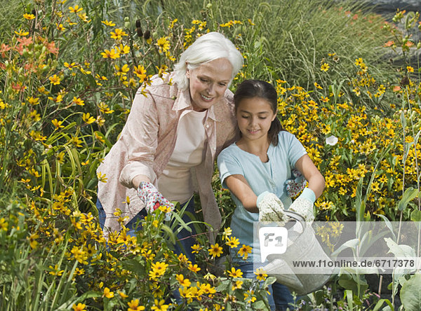 Grandmother and granddaughter watering plants