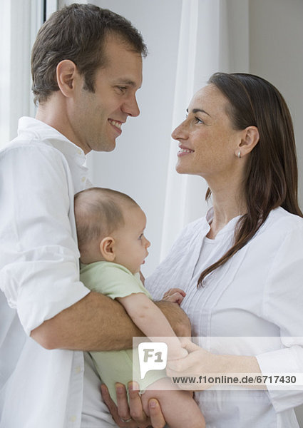 Couple standing face to face holding baby son