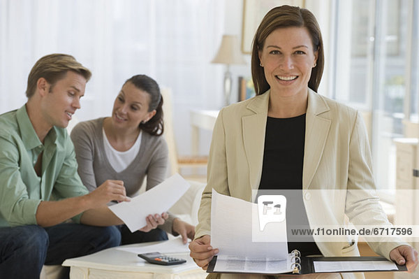 Female financial advisor with couple in background