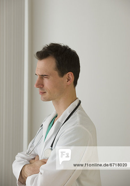 Male doctor looking out window pensively