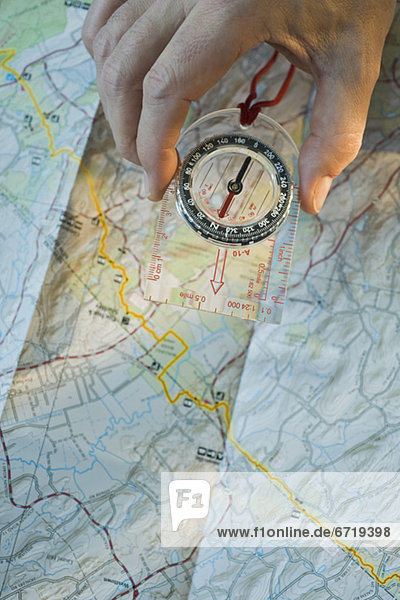 Man holding compass over map