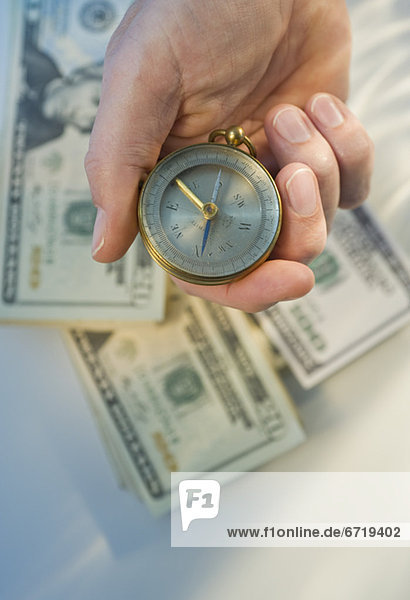 Man holding compass over money