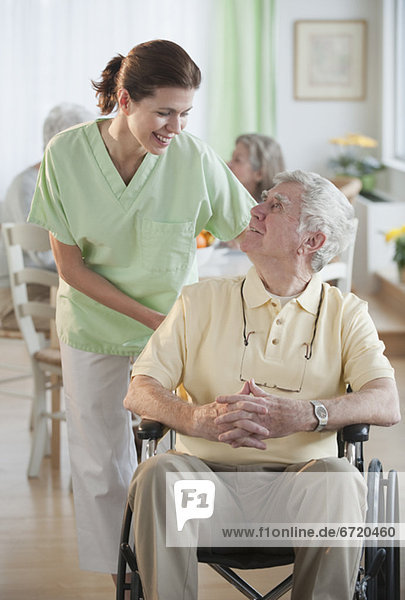 Nurse helping senior man in wheel chair