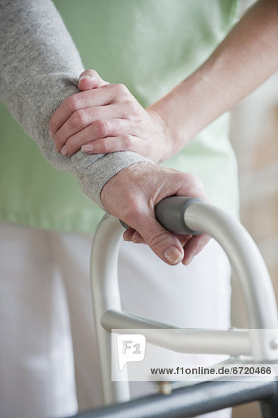 Nurse helping senior woman in walker