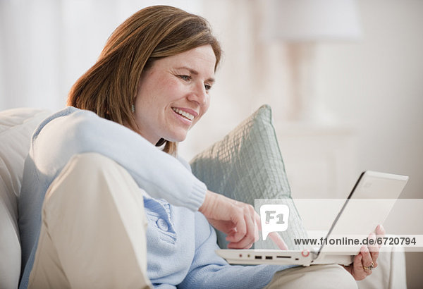 Mature woman using laptop on sofa