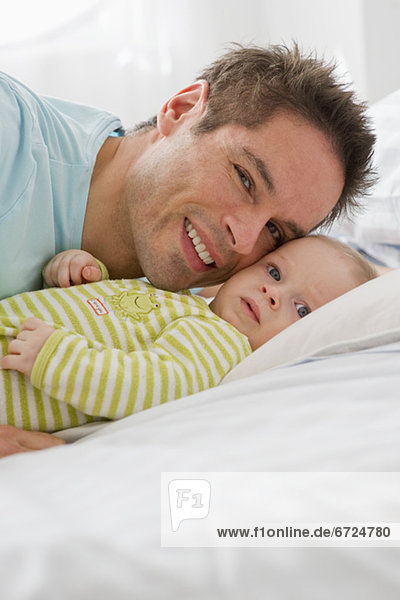 Father and baby lying down on bed