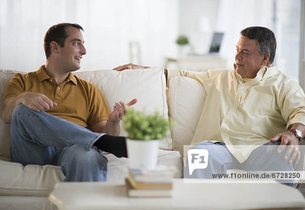 USA  New Jersey  Jersey City  Father and son talking on sofa in living room