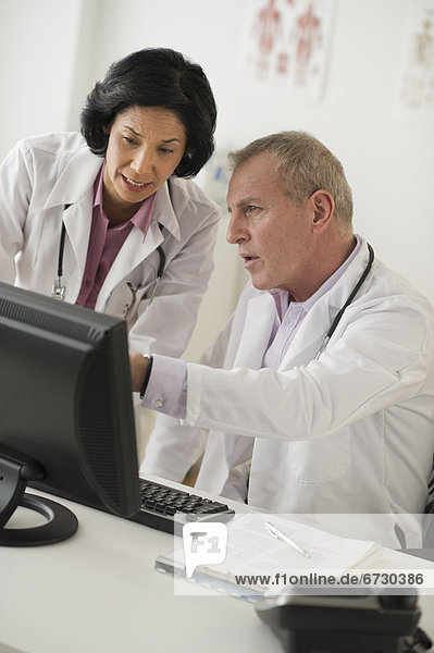 Pair of mature doctors discussing in front of computer
