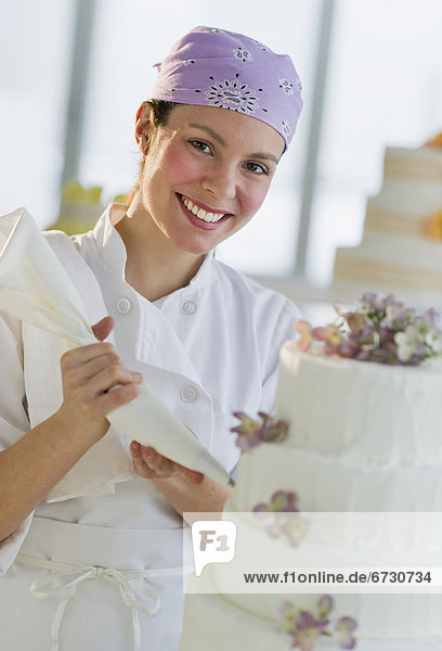 Portrait of happy young woman decorating wedding cake