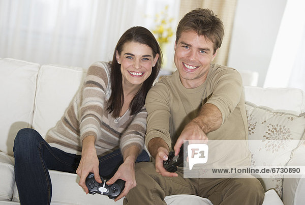 Couple sitting on sofa  playing video games