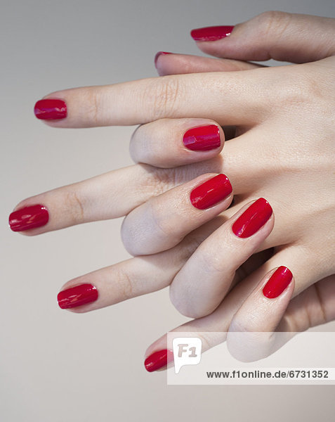 Close up of woman's clasped hands with red nail polish