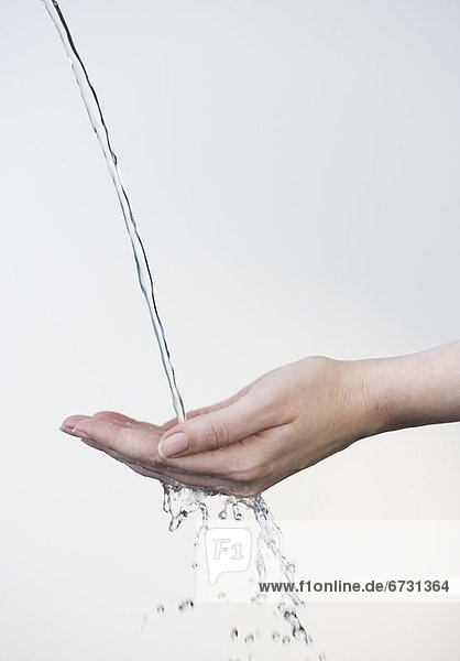 Close up of woman's hands under splashing water