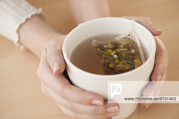 Woman holding cup with chamomile tea