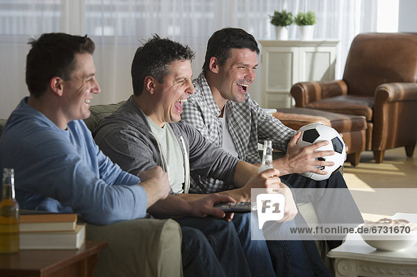 USA  New Jersey  Jersey City  three men watching television