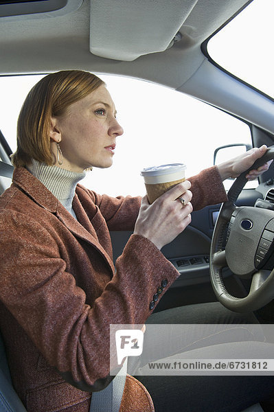 USA  New Jersey  Jersey City  woman driving car and drinking coffee