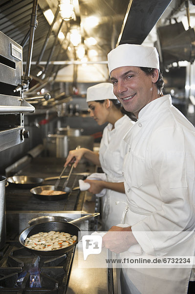 Chef and cook preparing food in commercial kitchen