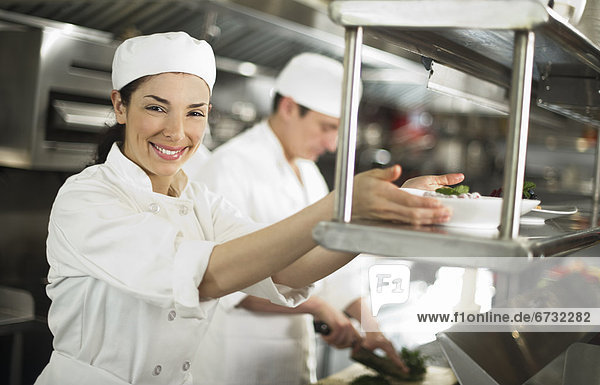 Chefs preparing food  woman looking at camera and smiling