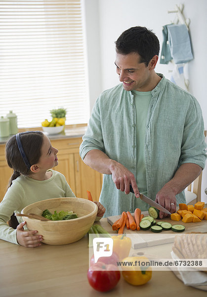 Daughter (8-9) and father preparing vegetables in kitchen
