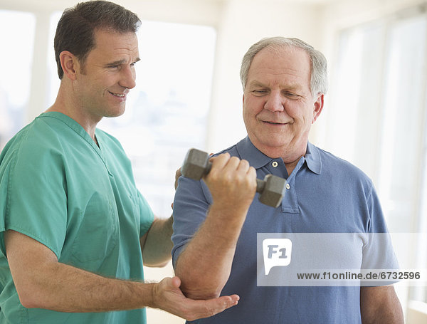 Man assisting senior man weight lifting