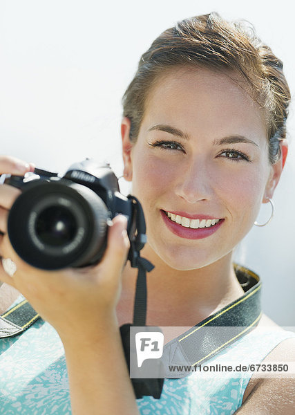 Portrait of young woman taking pictures with camera