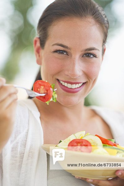 Portrait of young woman eating salad