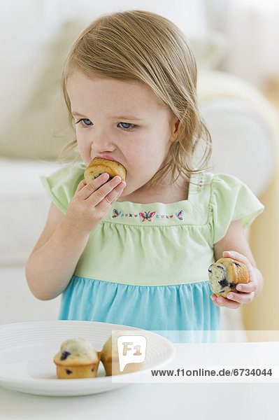 Girl (2-3) eating muffins