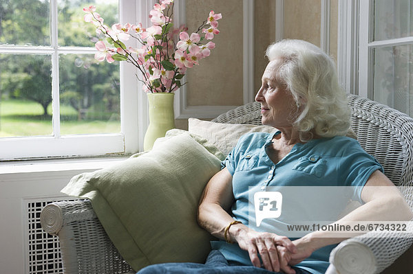 Senior woman sitting in chair looking through window