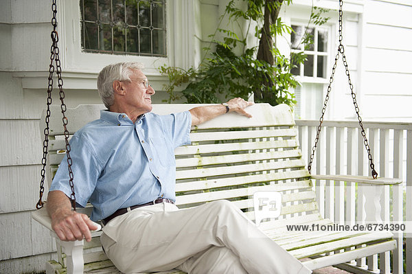 sitzend Senior Senioren schaukeln schaukelnd schaukelt schwingen schwingt schwingend Mann Vordach Schaukel