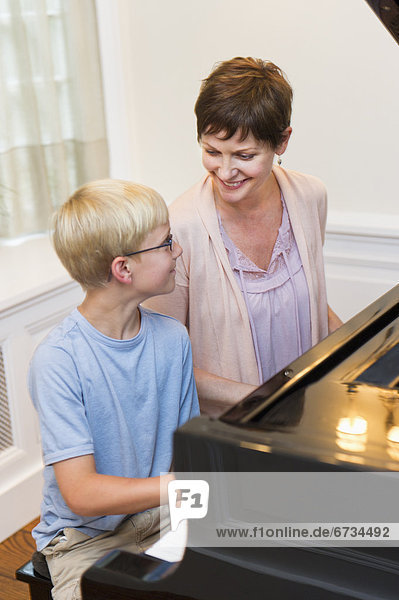 Mother and son (10-11) playing grand piano