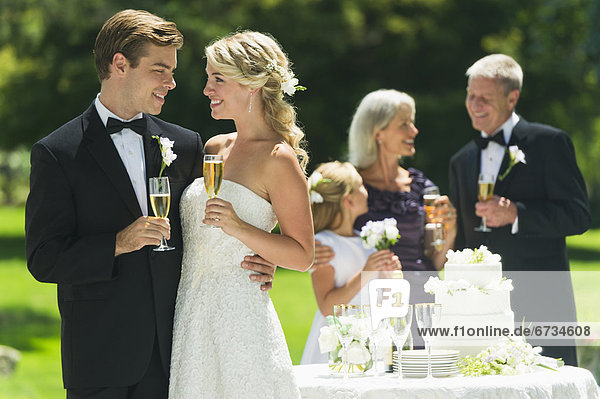 Married couple holding champagne flute  guests in background