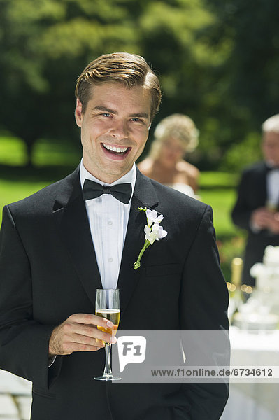 Portrait of groom holding champagne flute